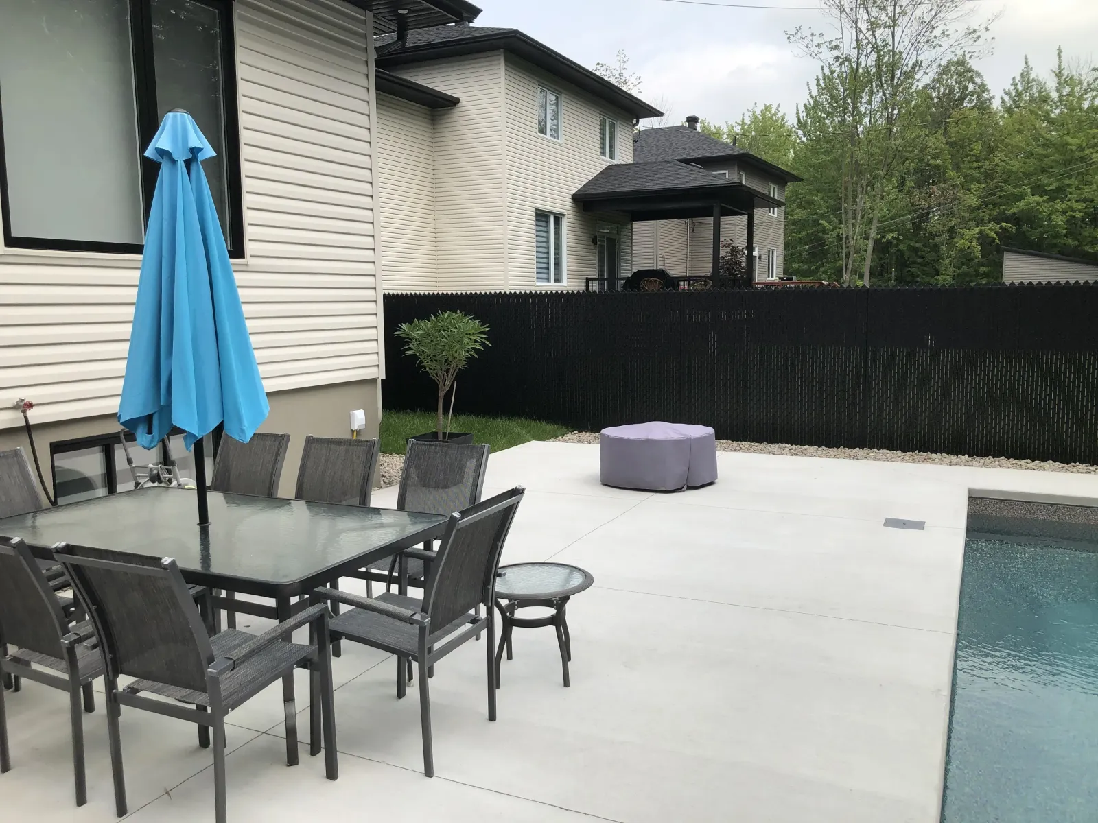 Cour arrière avec terrasse, piscine et clôture en maille de chaîne avec lattes d'intimité