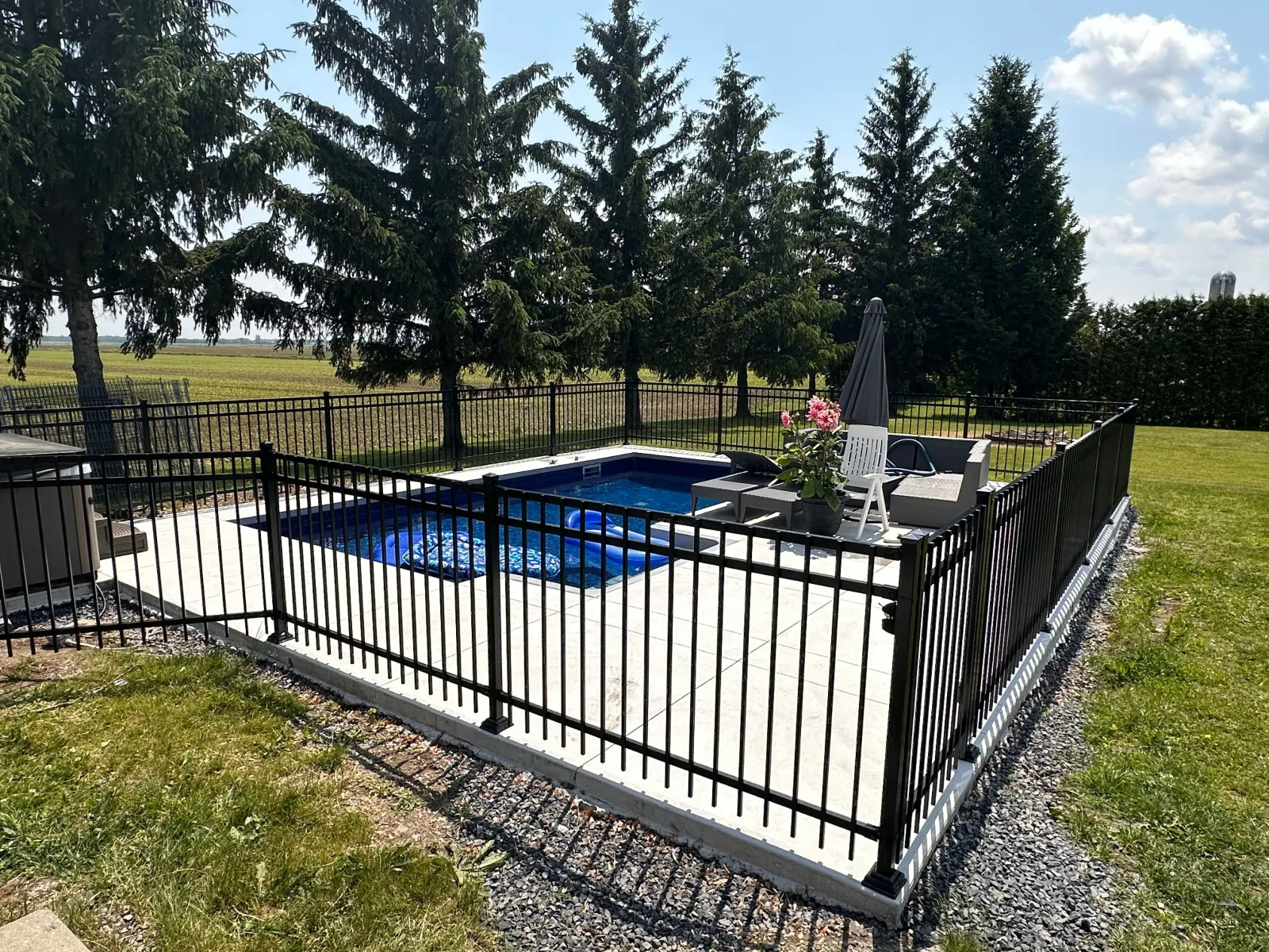 Clôture ornementale en aluminium autour d'une piscine avec conifères