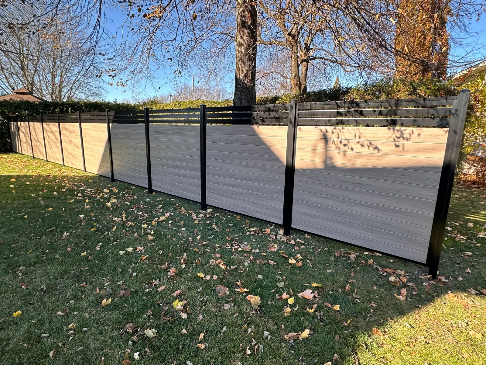 Clôture en PVC taupe dans une cour arrière en automne