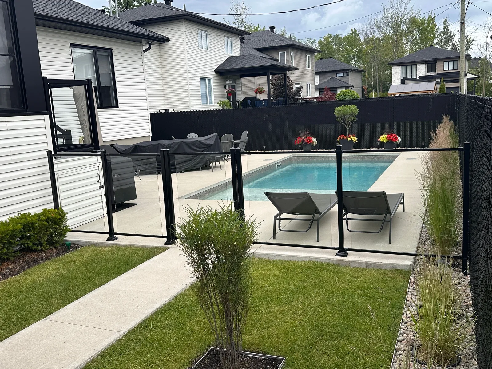 Clôture en verre trempé autour d'une piscine avec aménagement paysager moderne